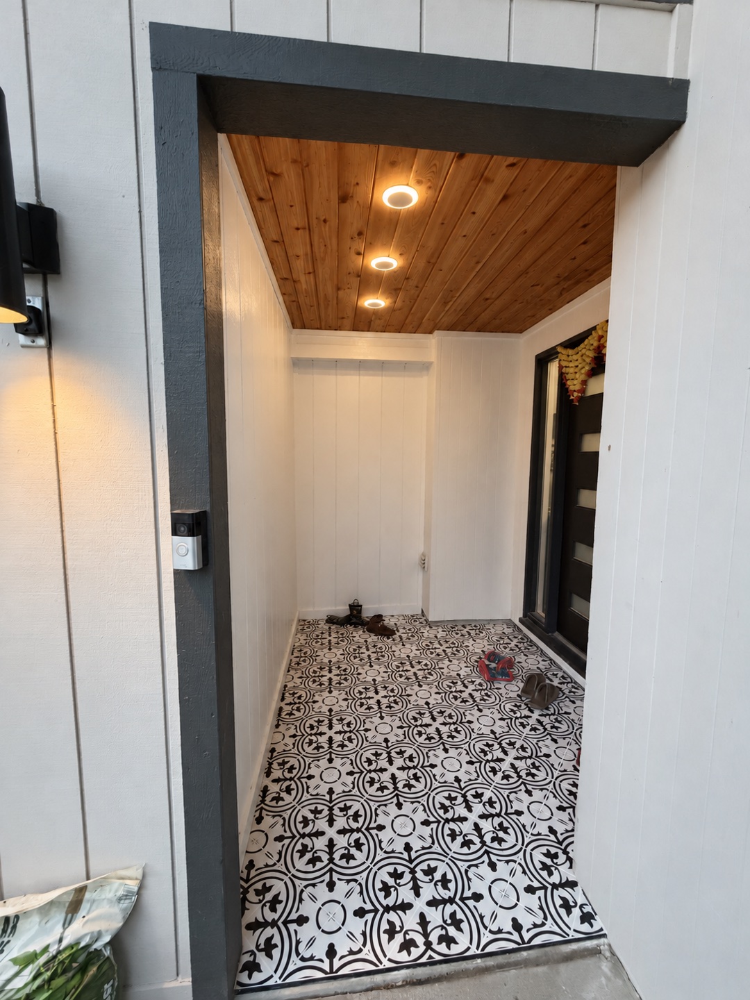 Entry with a wood ceiling, painted wall panels and patterned tile floor.