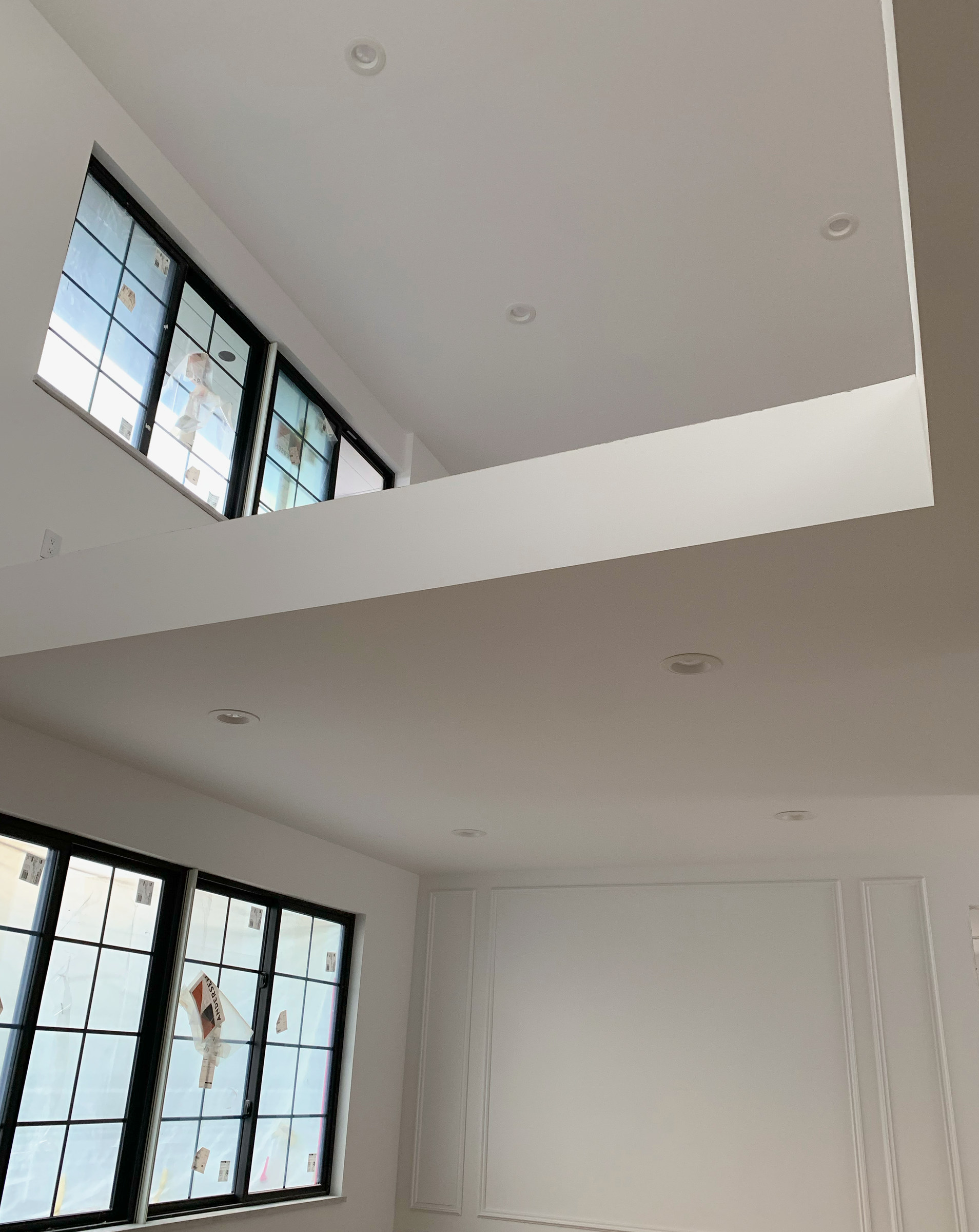 Double-height interior with black-framed windows and paneled walls.