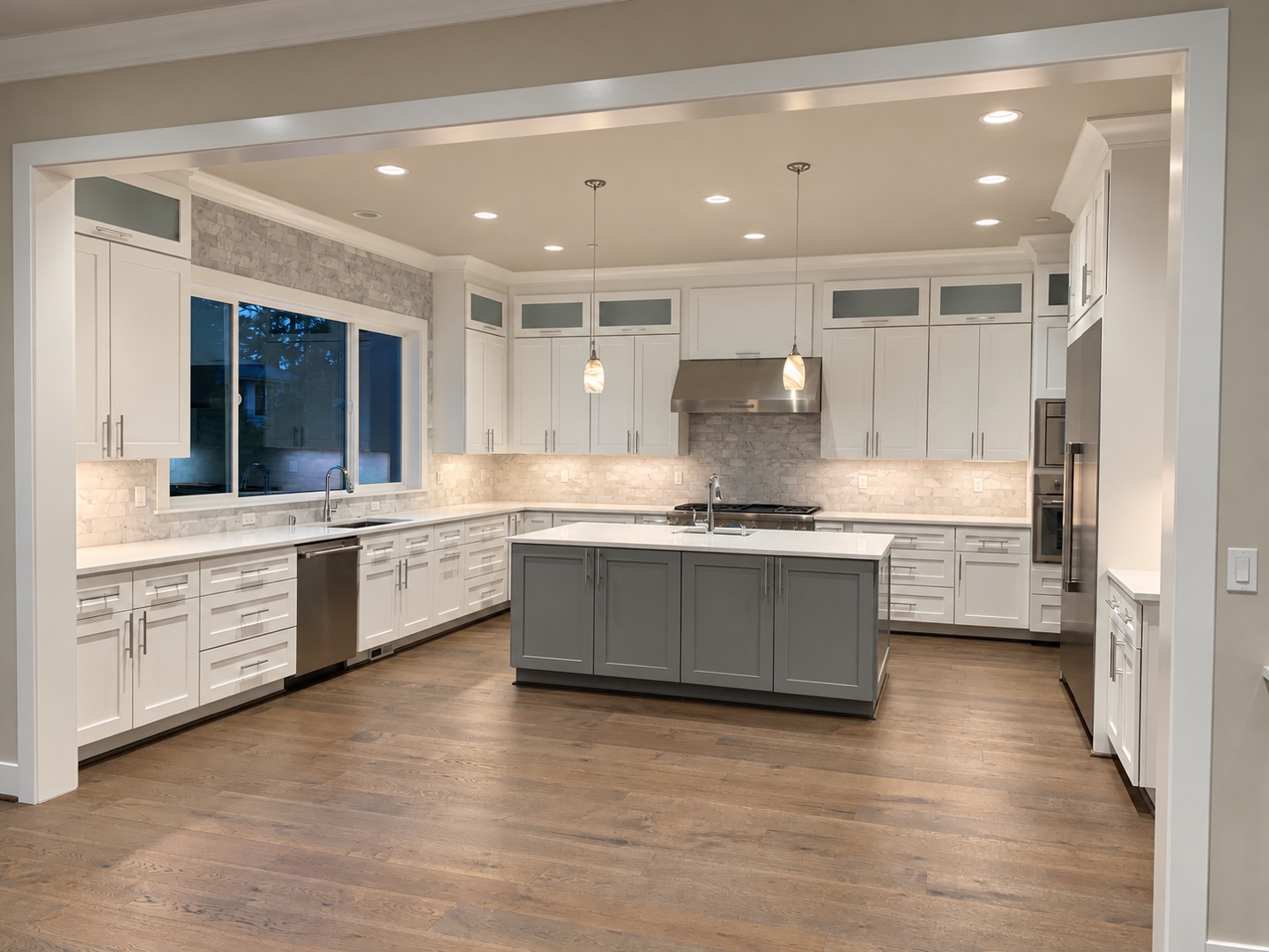 White kitchen cabinetry, a gray island, stone backsplash, and wood flooring