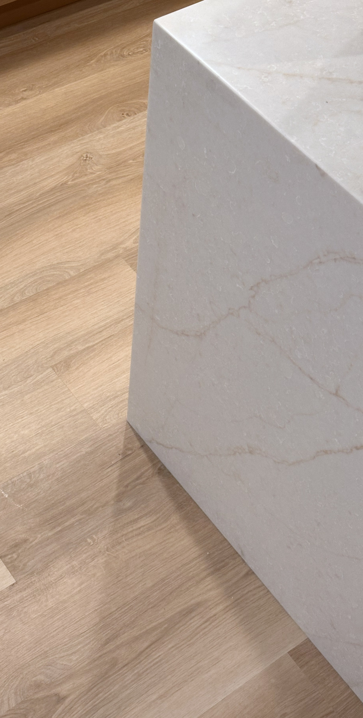 Waterfall countertop corner showing the original stone pattern beside wood flooring.